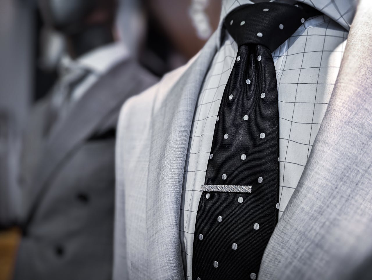 Elegant close-up of a polka dot necktie paired with a checkered formal shirt and suit.