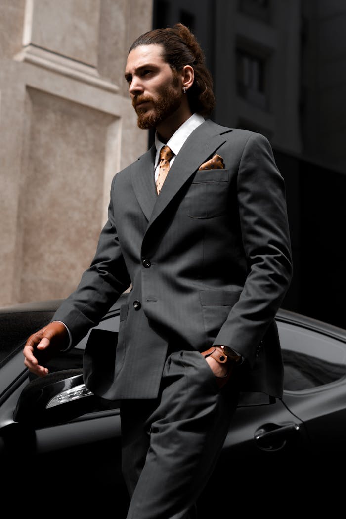 services-02 Sophisticated businessman in suit walking past a luxury sportscar in a city setting.