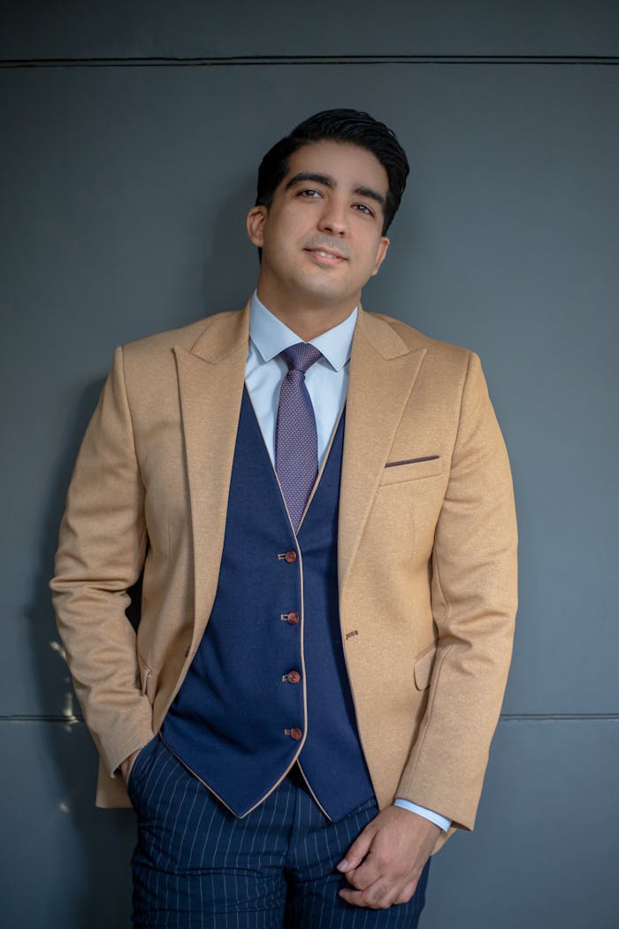 gallery-5 A portrait of a confident man in a beige suit and blue tie, exuding sophistication.